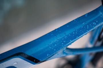 Some water raindrops on a blue carbon frame of a bicycle