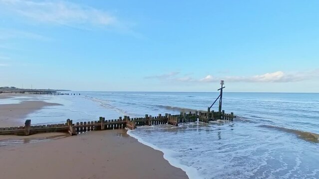 Waves crashing in to the wooden groynes and breakers on the North Norfolk coast. Captured in the seaside village of Walcott and Ostend on a bright autumn afternoon