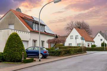 City street single-family modern houses Germany against warm sunset sky. German suburban small town...