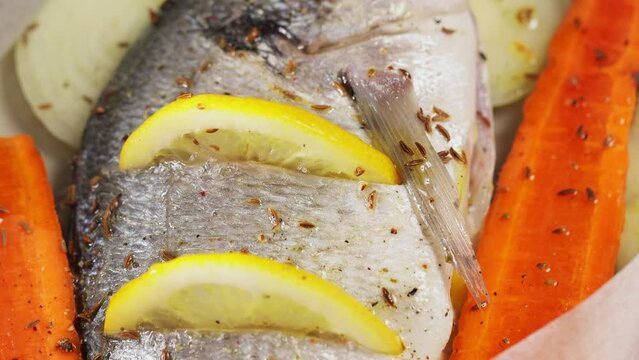 Dorado fish on baking sheet with vegetables, lemon and spices. Tilt down camera movement