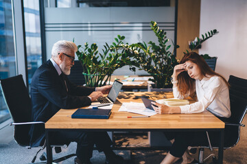 Male boss and female subordinate using gadgets in office