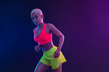 Sporty fit woman, athlete with dumbbells make fitness exercises on neon background. Download cover for music collection for fitness classes. Sports recreation. Beautiful black young woman.