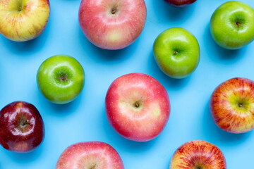 Variety of fresh apples on blue background.
