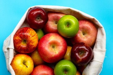 Variety of fresh apples on blue background.
