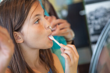 Young Girl Sampling a Taste of Gelato at the Ice Cream Shop. - obrazy, fototapety, plakaty