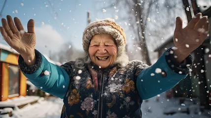 Fototapete Heringsdorf, Deutschland Elderly woman smiling and raising her hands in a snowfall in a village