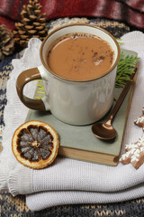 Cozy winter lifestyle concept. Mug of hot drink with vintage book and tasty homemade Christmas gingerbread cookies.