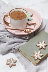 Fototapeta na wymiar Cozy winter lifestyle concept. Mug of hot drink with vintage book and tasty homemade Christmas gingerbread cookies.