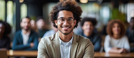 Picture of a mixed race professional with curly hair grinning while seated among coworkers