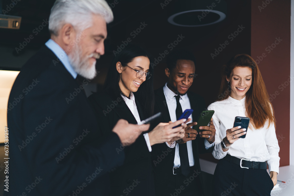 Wall mural Cheerful multiethnic colleagues using smartphones in office