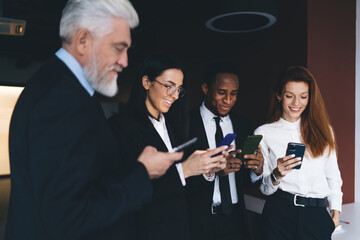 Cheerful multiethnic colleagues using smartphones in office