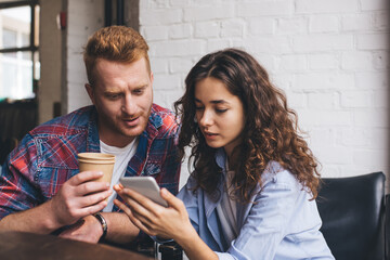Youngbest friends discussing content plan for web page in social media networks while using cellphone technology