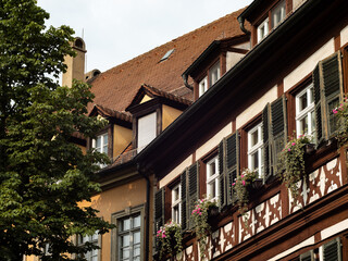 Half timbered building facade with beautiful flower pots. The houses are part of a historic old town in a German city. The ancient architecture is an attraction for tourists.