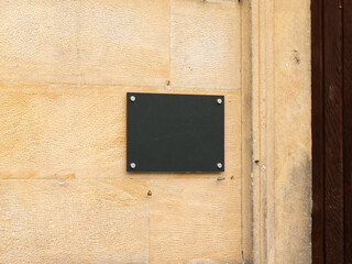 Blank dark sign on a building wall next to the entrance. Copy space to insert a logo or name of the...