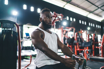 Fototapeta na wymiar Black man sitting in gym near equipment with blur of lights