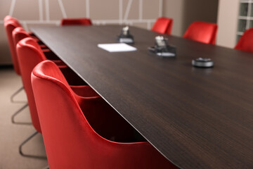 Stylish red office chairs and large wooden table in empty conference room
