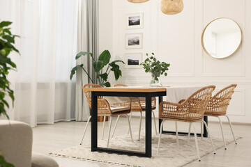 Stylish dining room with cozy furniture, mirror and plants