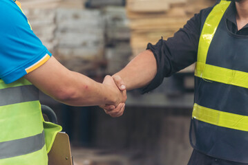 Close up warehouse worker shakehand together. Engineer man hands partnership. Diversity Coworker...