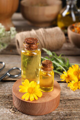 Bottles of essential oils and calendula flower on wooden table. Medicinal herbs