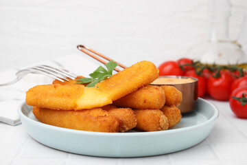 Tasty fried mozzarella sticks served with sauce and parsley on white tiled table