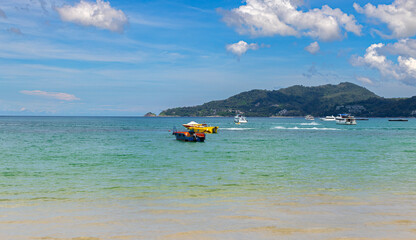 Patong Beach Phuket Thailand nice white sandy beach blue Skies with some clouds and turquoise waters Palms tree people swimming long tail boats sunrise sunset