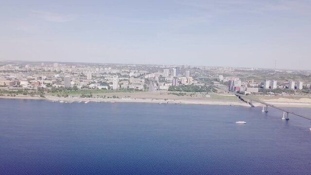 Aerial view flying slowly along the Volga River with the Volgograd-Krasnoslobosdk Bridge showing pylons and architecture.  On the Volga River, Volgograd, Russia.