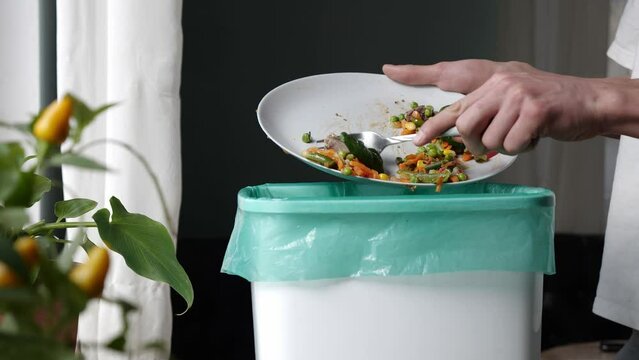 Food loss in household. A lot of food is wasted. Man throws half-eaten meal leftovers in the trash can