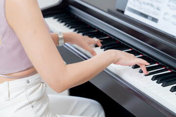 Beautiful Asian woman playing the piano happily In her house on holidays