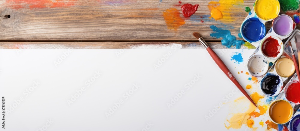 Poster close up flat lay of a watercolor palette paintbrushes and paper on a wooden background the scene ha