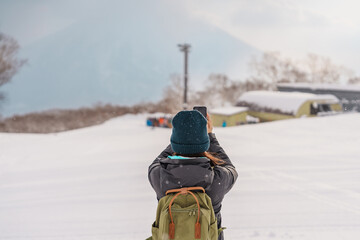 Woman tourist Visiting in Niseko, Traveler in Sweater sightseeing Yotei Mountain with Snow in...
