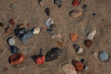Multicolored sea pebbles on sand through seawater, Baltic Sea, Curonian Spit, Kaliningrad region,...