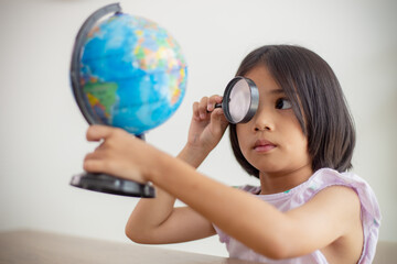 Asian little girl is learning the globe model, concept of save the world and learn through play activity for kid education at home.