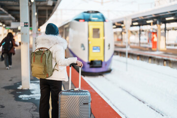 Woman tourist with bag in Train Station platform with Snow in winter. Hakodate, Hokkaido, Japan.Travel and Vacation concept - obrazy, fototapety, plakaty