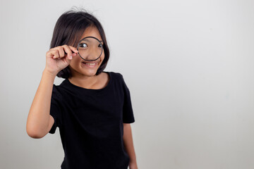 little girl looking through a magnifying glass