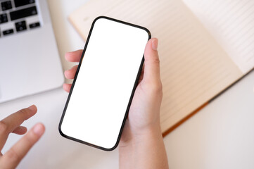 A woman using her smartphone at her desk. A white-screen smartphone mockup in a woman's hand.