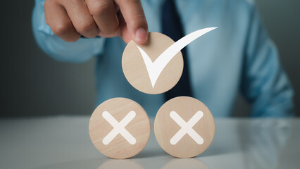 Businessman selects correct check mark symbol on wooden circle plank for business proposal and...