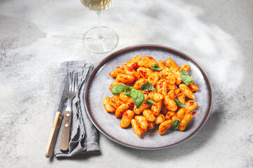 Traditional Italian potato Gnocchi with tomato sauce and fresh basil on gray plate, marbled backround.