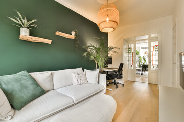 a living room with green walls and white couches in the center of the room is an open door leading to another room
