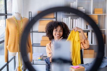 Young African American vlogger woman influencer. Smiling retail store owner enjoys selling live...