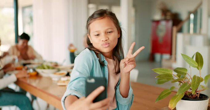 Selfie, peace or children and a girl in a home, posing with her family on a blurred background. Kids, social media and hand gesture with a happy young female child taking a profile picture photograph