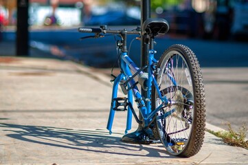The back view of bicycle is locked at the pole on the sidewalk. The front wheel was stolen from the...