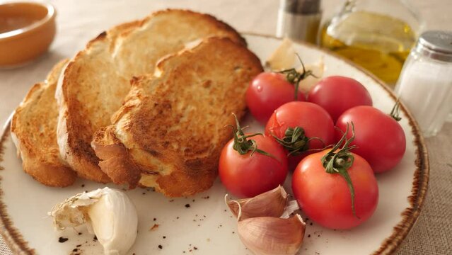 Preparation of appetizing Catalan tapas Pan con tomate, grilled bread topped with mixture of grated tomatoes with garlic and olive oil. Ingredients ready for cooking served on table