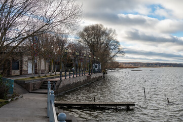 Small embankment with pier for boats and on the lake bank. Small street of the province town.