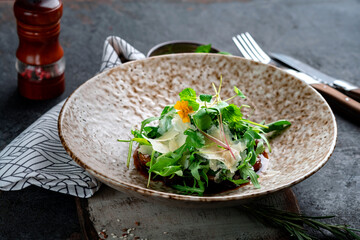 Salad with herbs and prunes on a ceramic plate on a dark table. Fresh salad with low calories