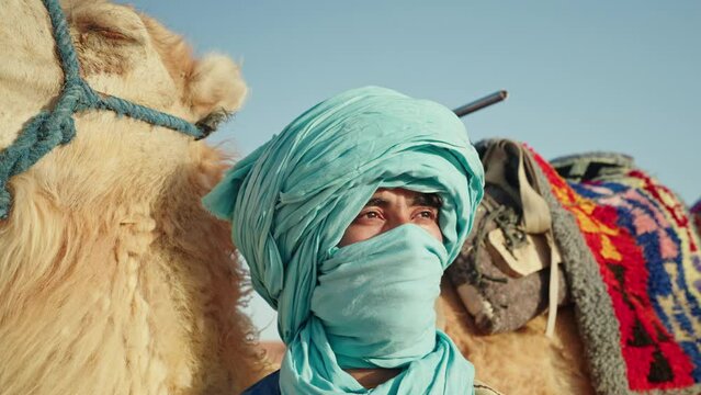 Headshot of berber man with turban near camel in the Sahara desert, Morocco