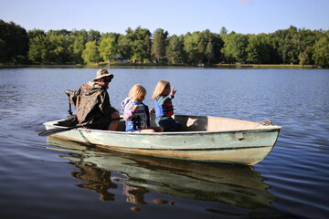 Fototapeta na wymiar Little Girl Children Riding in Small Fishing Boat in Lake with their Dad