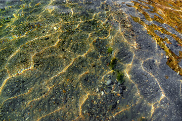 Patterns of the sun breaking through crystal clear water on the seabed. Perfectly clean sea water and the seabed near the shore. View of the seabed near the shore through clear water.