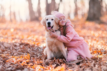 a little girl lovingly embraces her dog in a bright autumn meadow