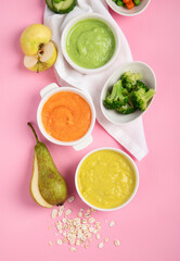 Bowls with baby food on pink background. Healthy eating concept.