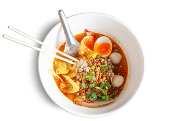 Tom Yum Kung Noodle with spicy chili soup in bowl isolated on white background. Thai Food delicious taste hot and appetizing ingredient, lemon, egg, meat. Instant noodle pork meatball,  top view